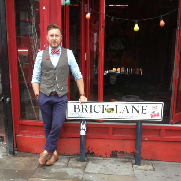 Dapper Chap standing by Brick Lane street sign