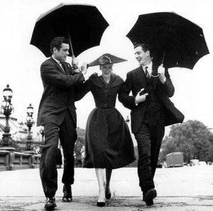 Old photograph of woman with two men holding umbrellas