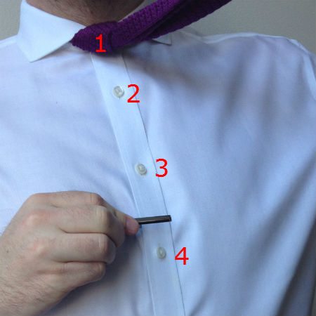 Man positioning a tie clip on shirt