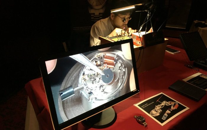 Watchmaker placing gear on movement