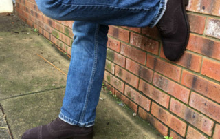 Man In Jeans And Brown Shoes Against Wall