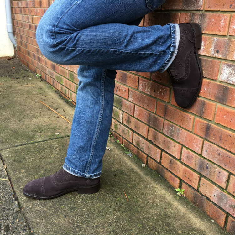 Man In Jeans And Brown SHoes Against Wall