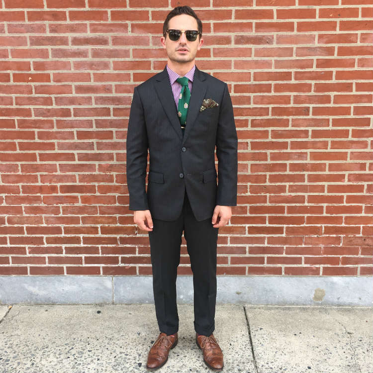 Man in grey suit against brick wall