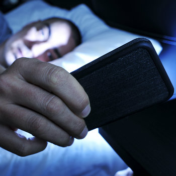 Man looking at smartphone in bed