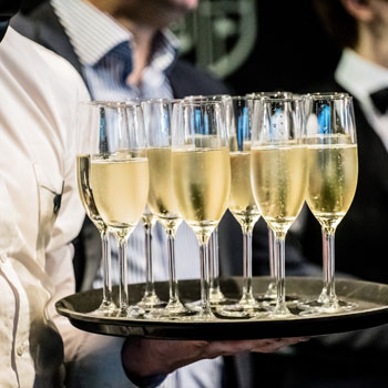 Waiter With Bow Tie Serving Champagne Flutes On A Platter