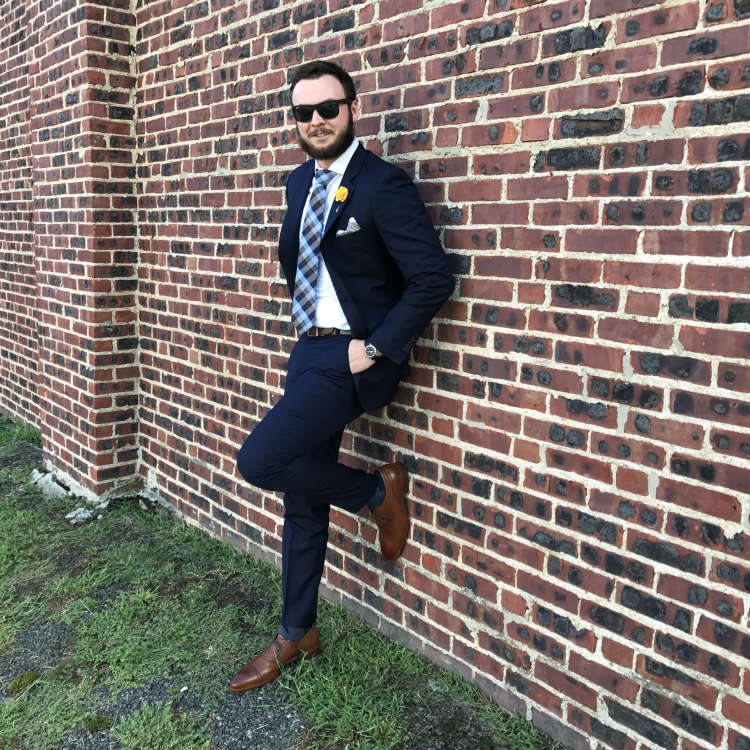 man in blue suit against brick wall