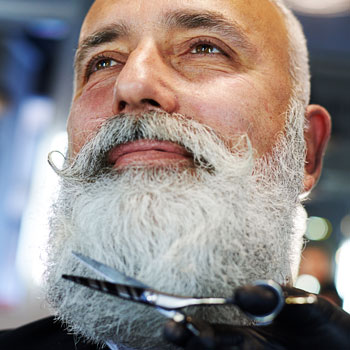 Grey Haired Man Cutting Beard With Scissors
