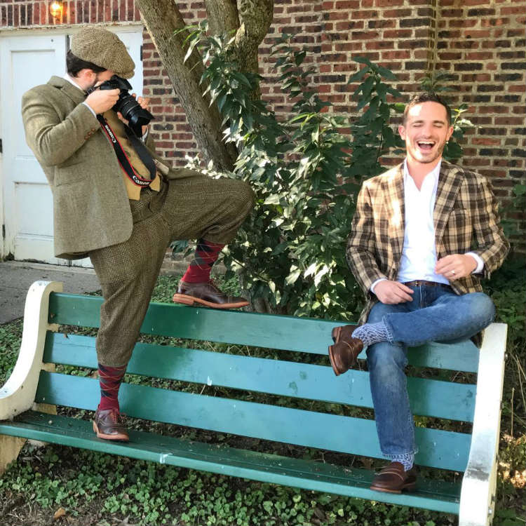 Two men on a bench taking pictures