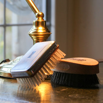 two beard brushes on a leather desk under lamp
