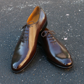 brown wholecut shoes on concrete