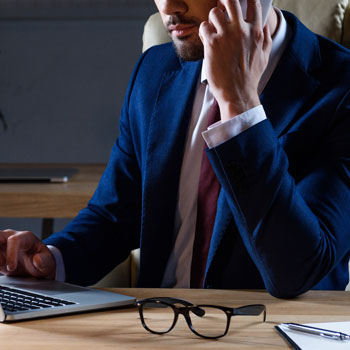 Businessman At Desk Answering Smartphone